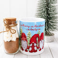 Mug with Christmas design featuring gnomes and a jar of hot chocolate mix on a white surface.
