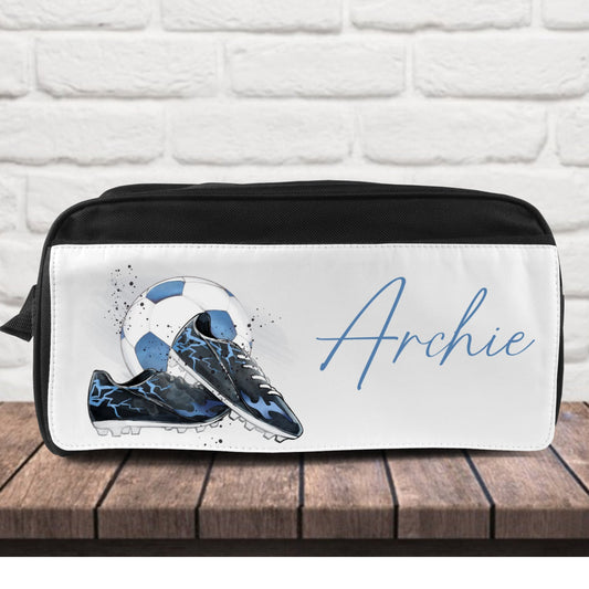 Personalized shoe bag with soccer cleats and the name 'Archie' on a white brick background.