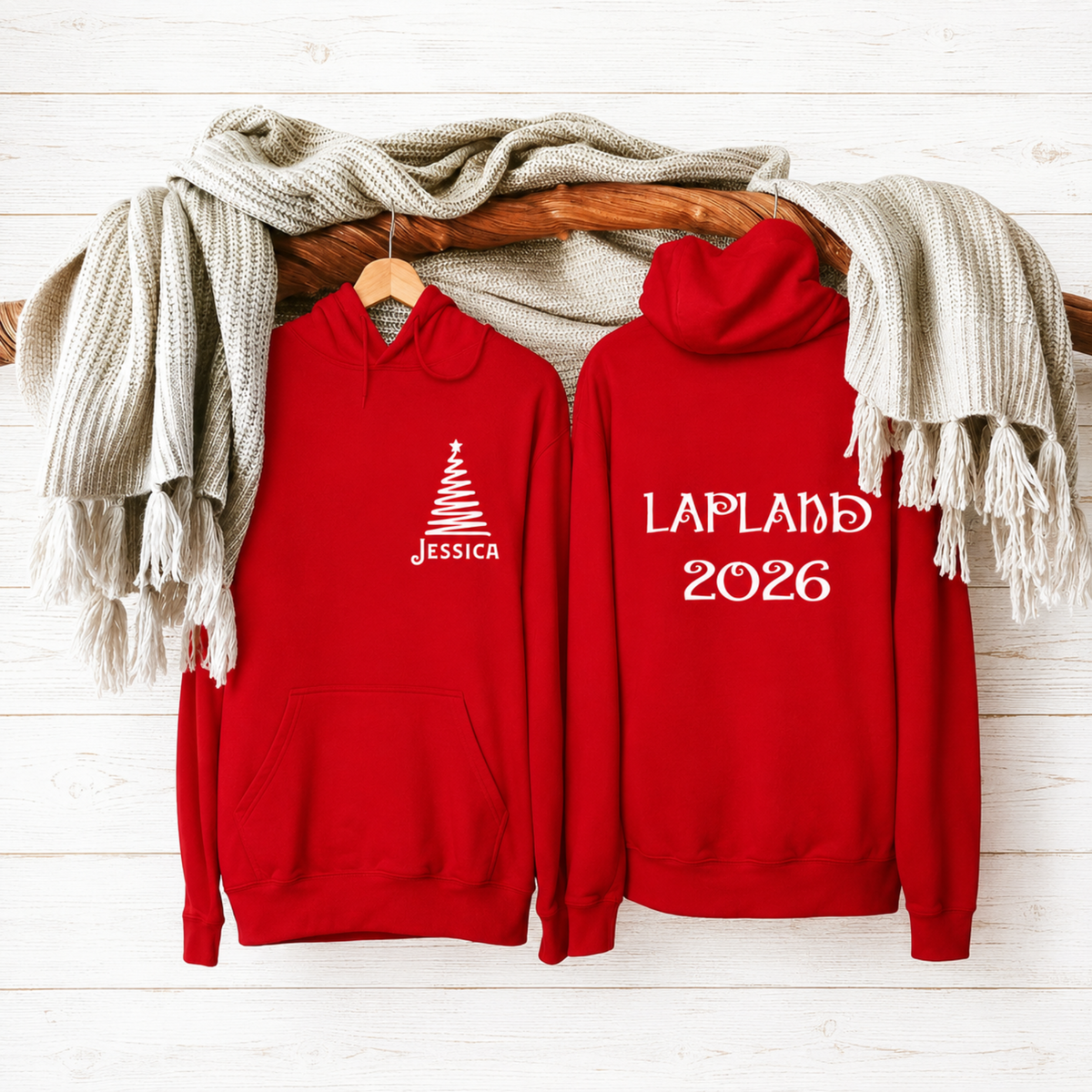 Two red hoodies with personalized text on a wooden surface with a scarf.