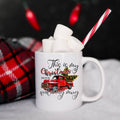 White mug with Christmas-themed design, filled with hot chocolate and marshmallows, against a dark background.