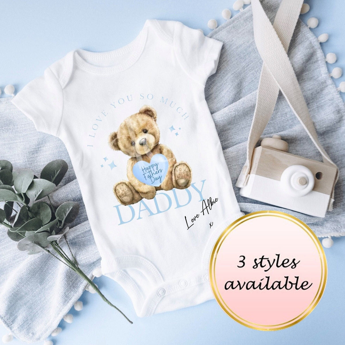 Baby onesie with teddy bear design on a light blue background
