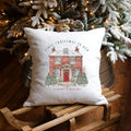 Decorative pillow with 'First Christmas in Our New Home' text on a wooden sled in front of a decorated Christmas tree.