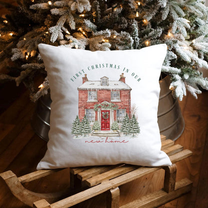 Decorative pillow with 'First Christmas in Our New Home' text on a wooden sled in front of a decorated Christmas tree.