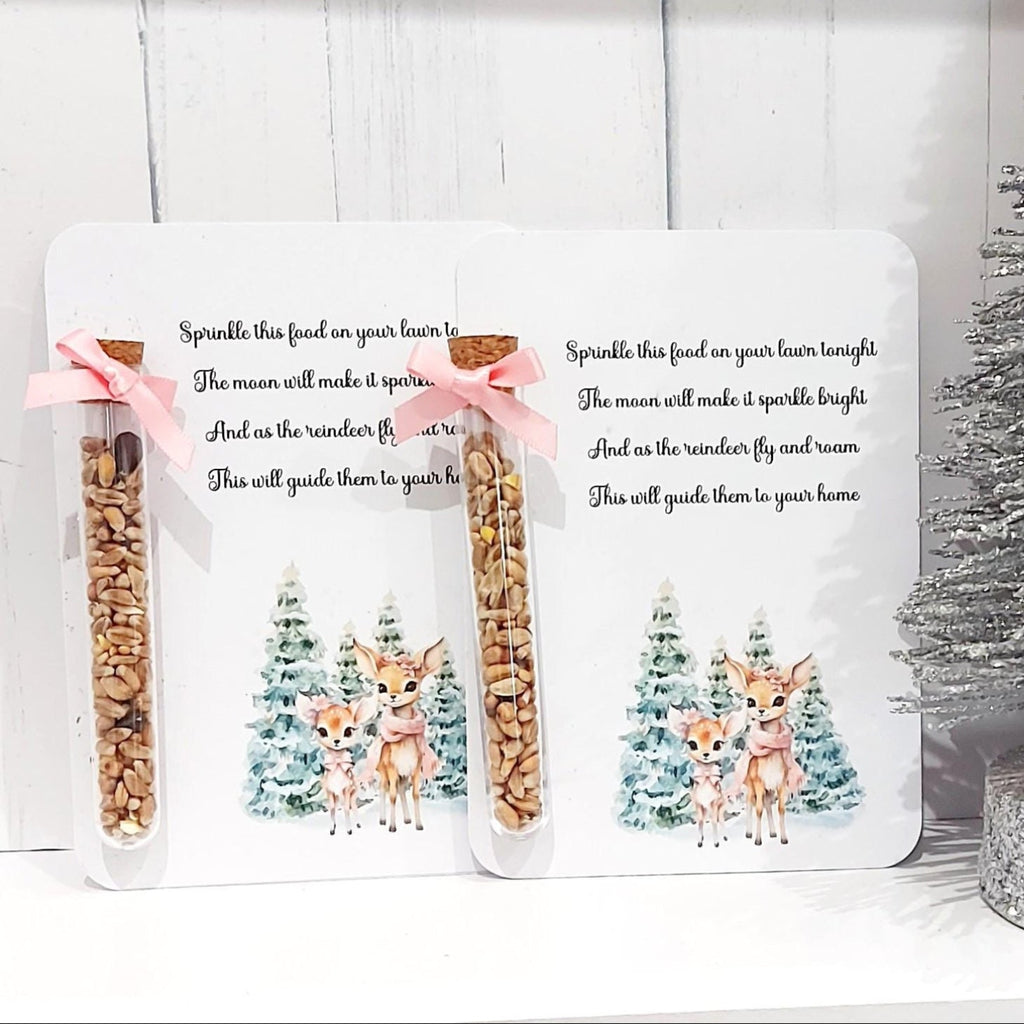 Two packages of birdseed with a deer design on a white background, next to a small decorated Christmas tree.
