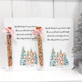 Two packages of birdseed with a deer design on a white background, next to a small decorated Christmas tree.