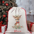 Drawstring bag with a deer design and 'Olivia' text, placed in front of a decorated Christmas tree.
