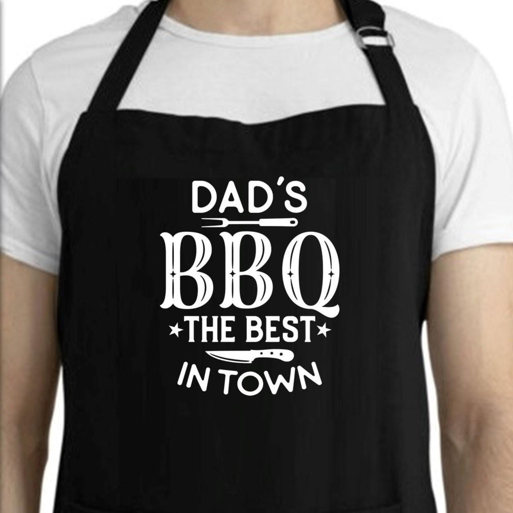 Black apron with 'Dad's BBQ The Best In Town' text worn by a person.