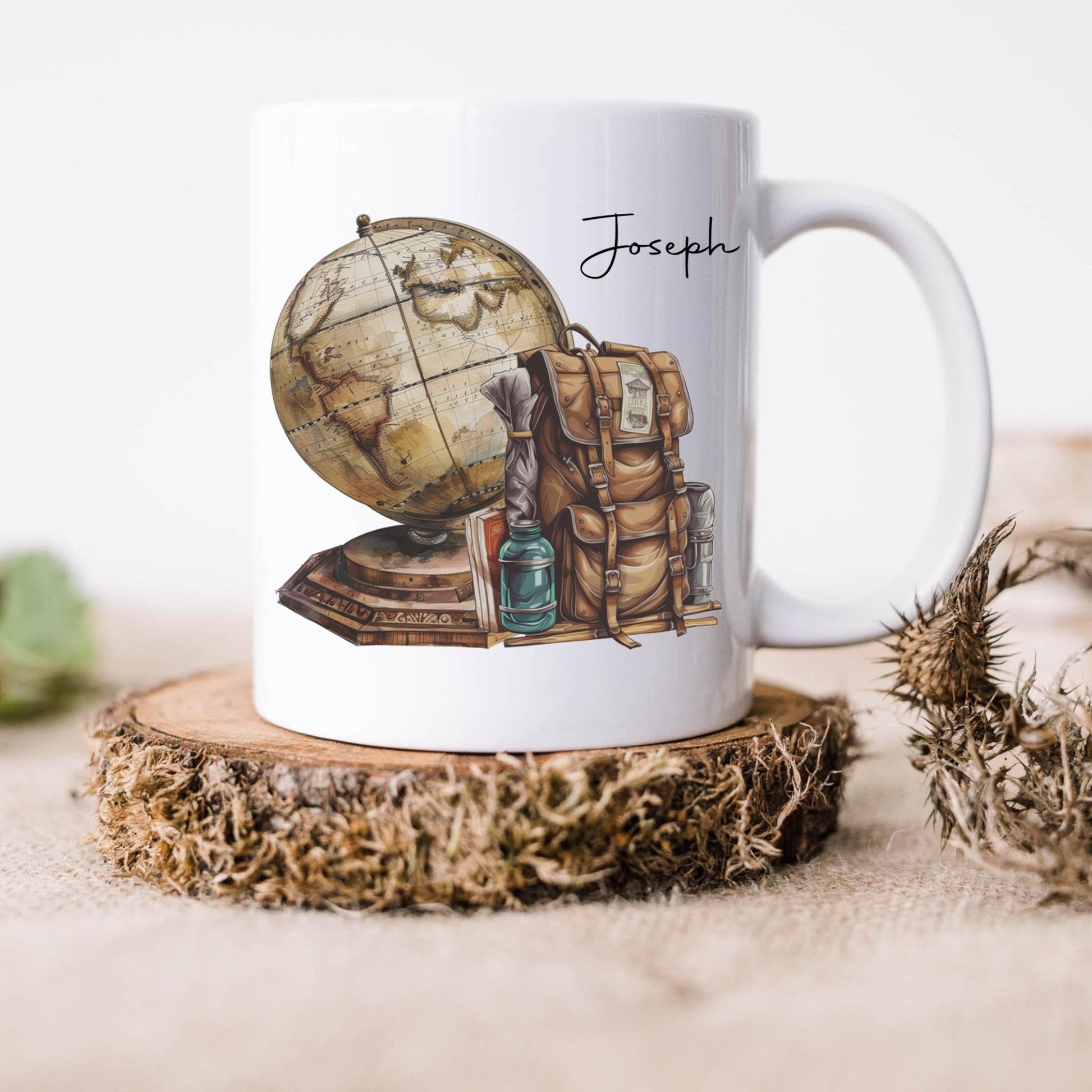 A white ceramic mug with a vintage globe and rucksack design, personalised with the name 'Joseph' on the front, displayed on a wooden stand with a matching coaster.