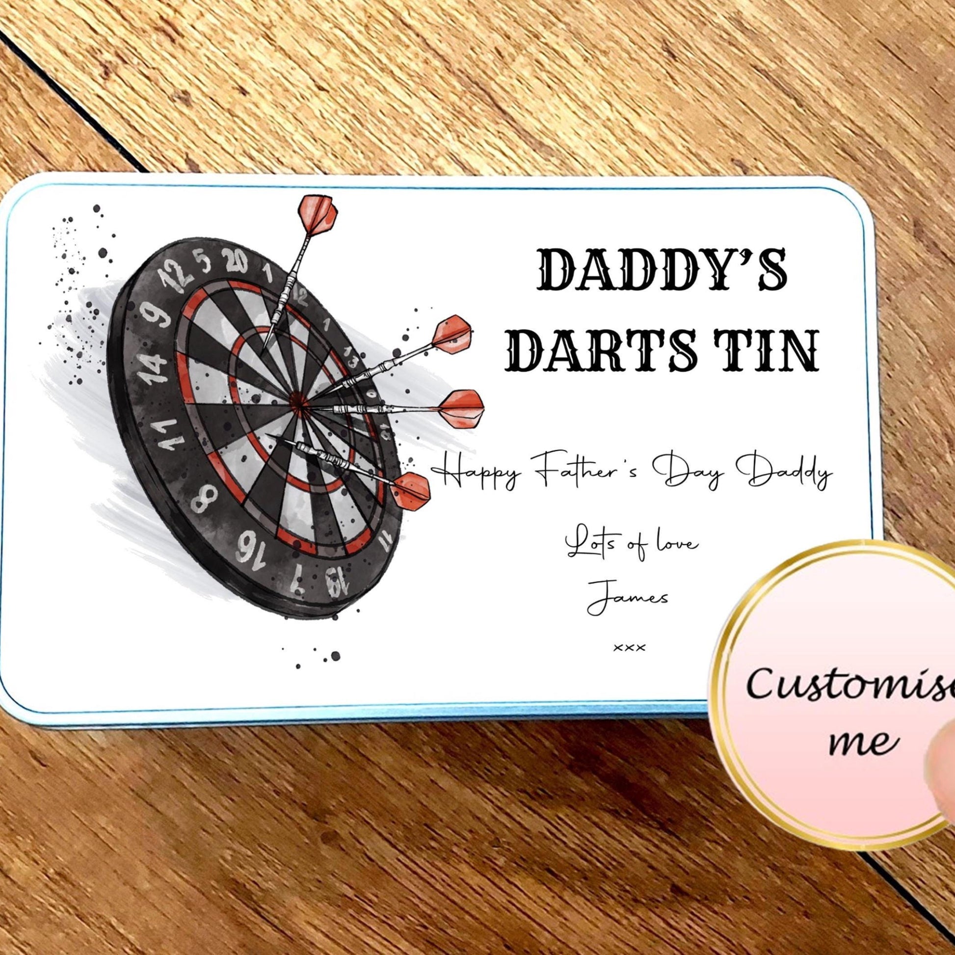 Personalized dart tin for Father's Day on a wooden surface with a hand holding a 'Customise me' button.