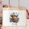 Tote bag with a highland cow illustration wearing a hat and scarf.