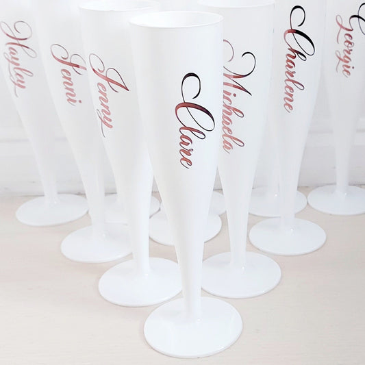 A set of personalized rose gold reusable champagne flutes with names printed on them.
